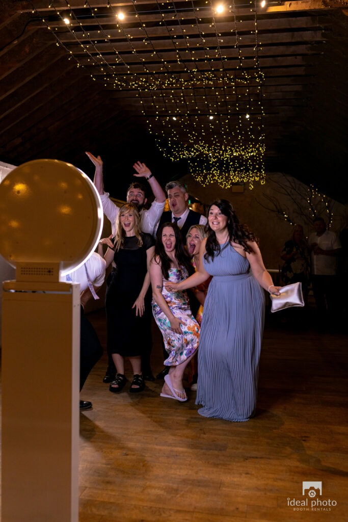 Group of people posing in front of a digital selfie booth at an event.